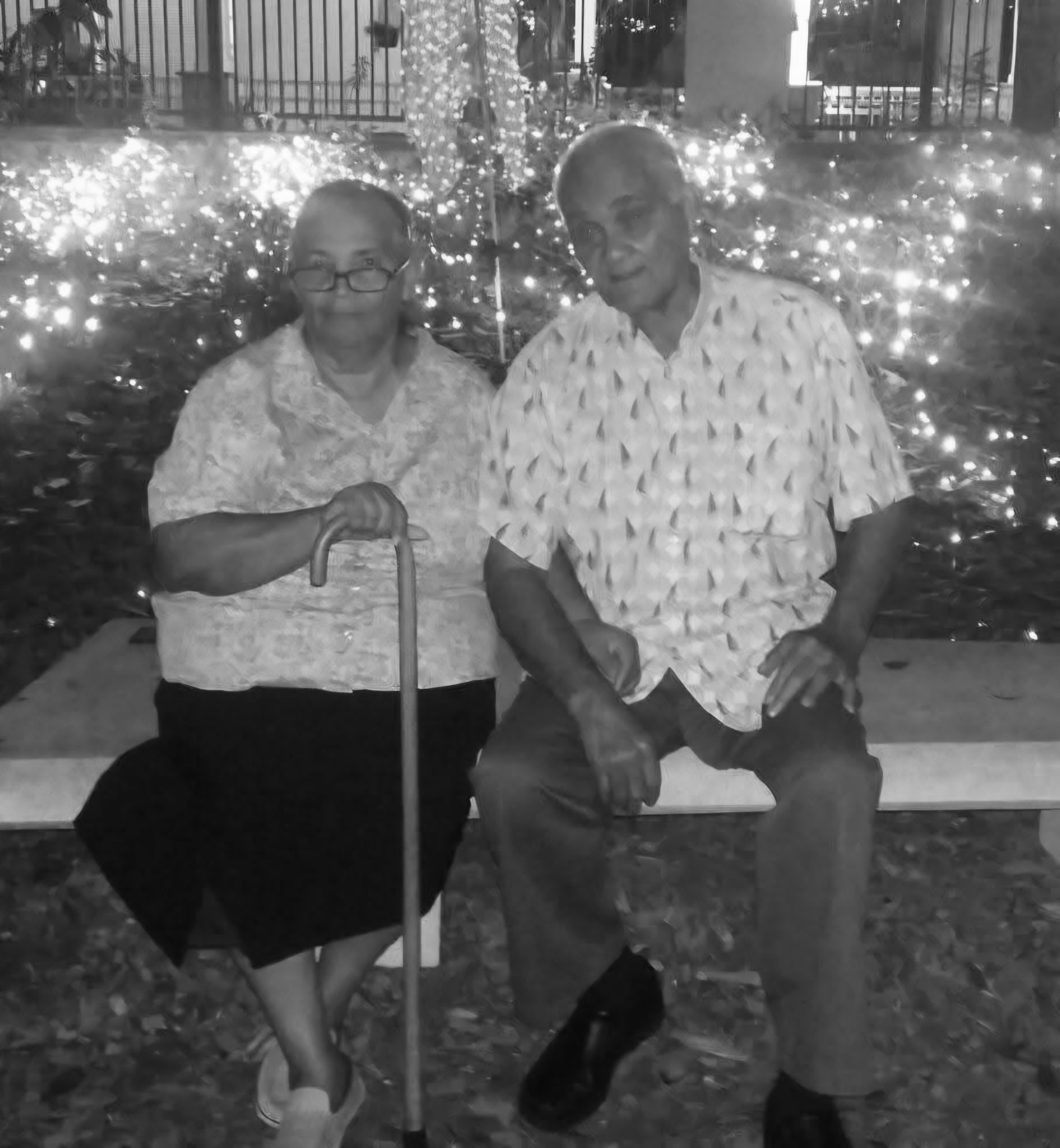 Maria and Moises seated together surrounded by holiday lights